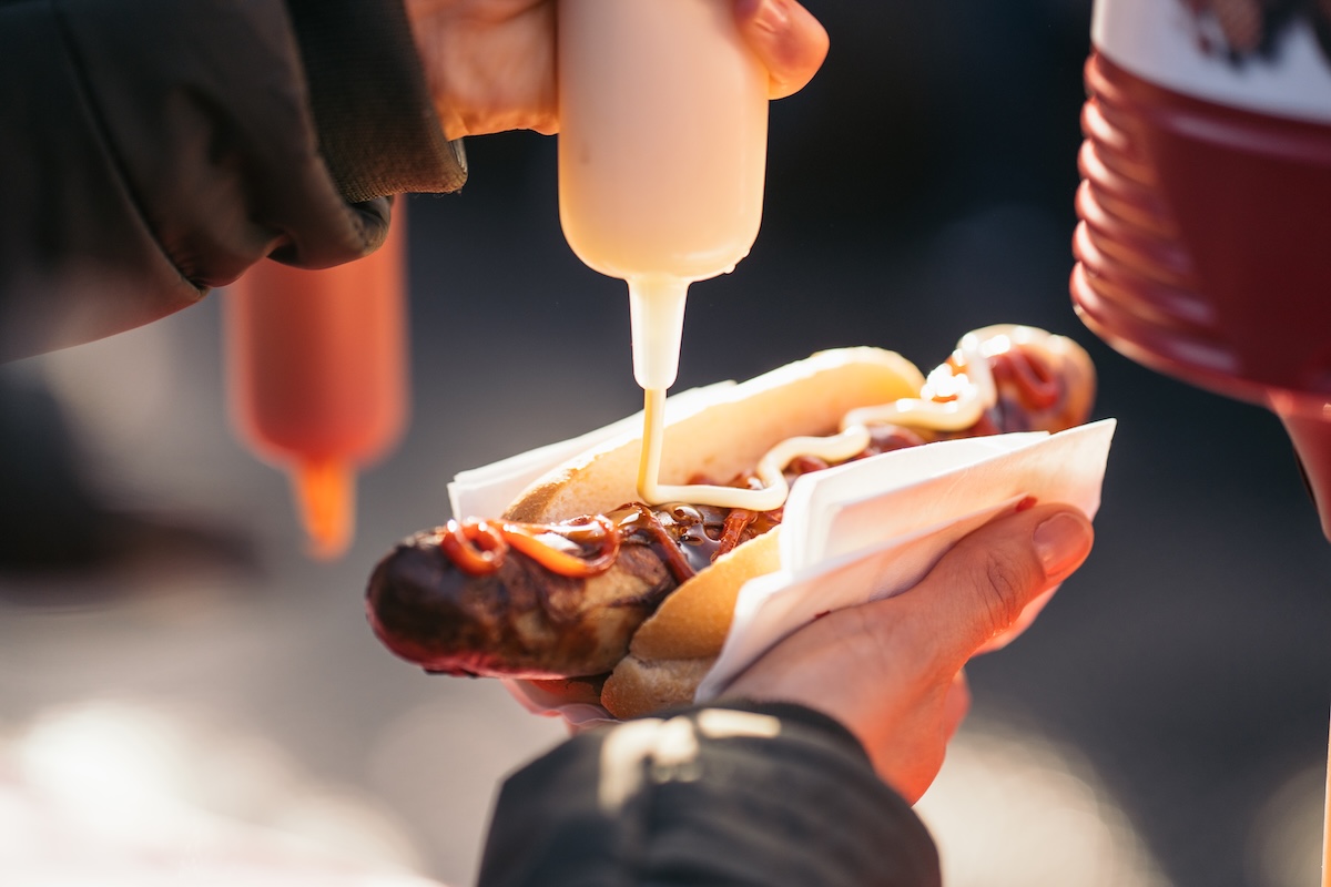 Mann macht sich Senf auf seine Bratwurst.