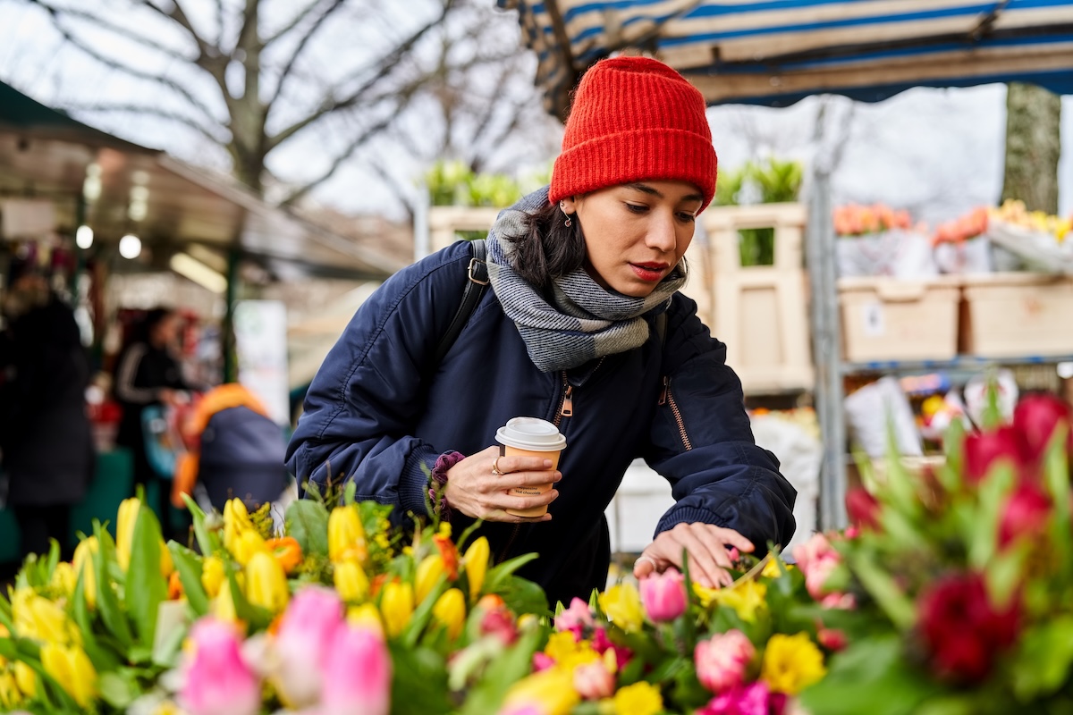 Frau schaut sich Blumen auf dem Wochenmarkt an.